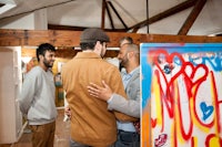 a group of people standing in front of a painting with graffiti on it