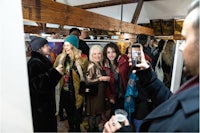 a group of people looking at paintings in an art gallery