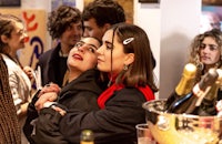 a group of people standing around a bottle of wine