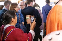 a woman taking a picture of a crowd of people