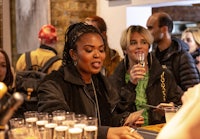 a group of people at a bar with glasses of wine