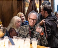 a man holding a glass of wine in front of a crowd of people